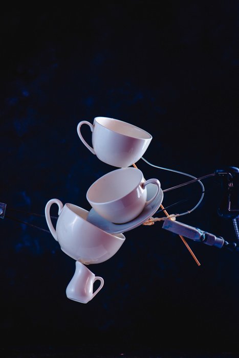Креативная идея фотографии брызг кофе, балансирующих на темно-синем фоне падающих кофейных чашек