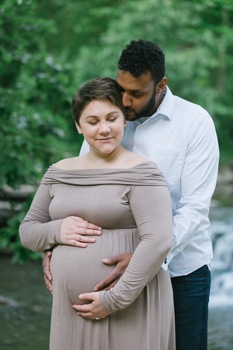 Романтический снимок мужчины, обнимающего свою беременную жену, сделанный свадебным фотографом