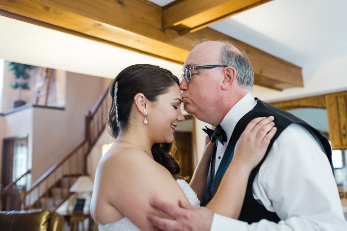 Прекрасный момент, когда отец целует голову невесты, запечатленный свадебным фотографом