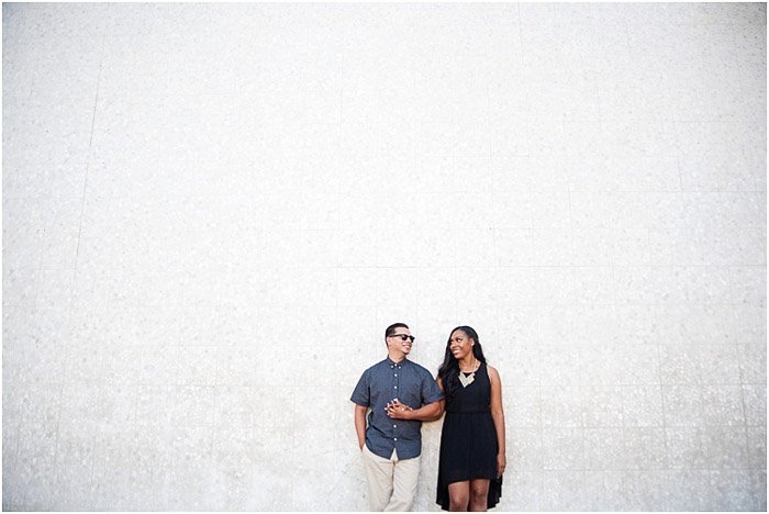 Фотография помолвки пары, стоящей на фоне просторной белой стены