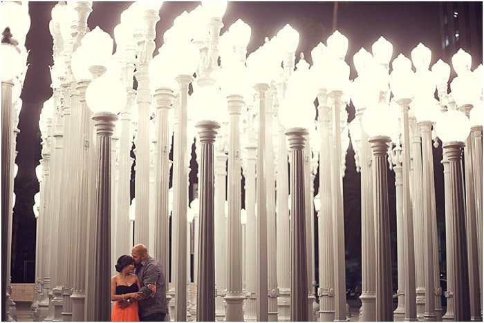 Романтическая фотография помолвки пары перед колоннами из белых ламповых скульптур