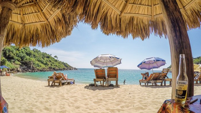 Красивая пляжная сцена в обрамлении соломенных зонтиков - работа фотографа в путешествиях