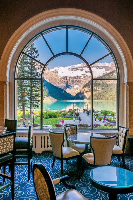 Потрясающий горный пейзаж, снятый через большое стеклянное окно с интерьером ресторана на переднем плане - окно как заработать деньги фотографией путешествий