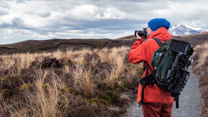 Фотограф в красной куртке снимает пейзаж