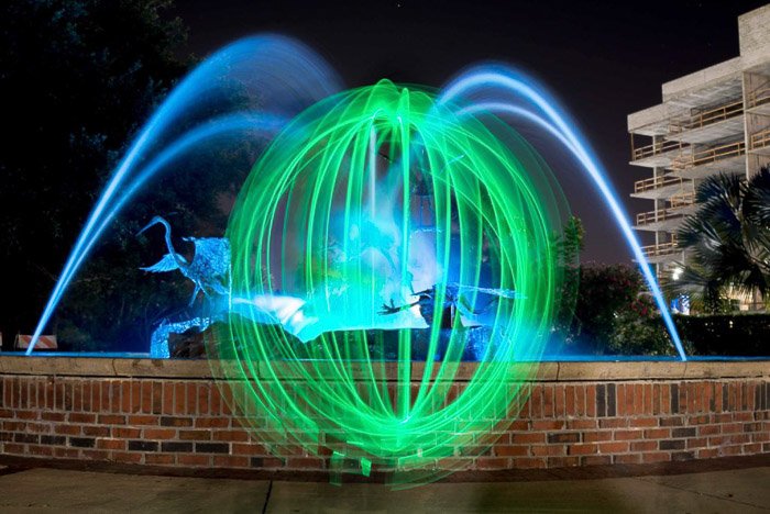 Зеленая световая сфера перед фонтаном ночью.