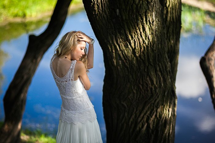 Портретная съемка на природе девушки, позирующей у дерева и воды в парке Санкт-Петербурга