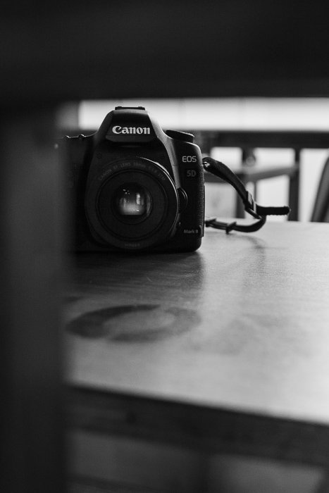 Черно-белая фотография зеркального фотоаппарата canon на столе.