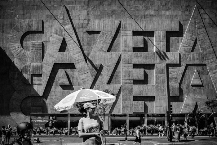 Черно-белый снимок уличной фотографии девушки, стоящей перед резной каменной стеной