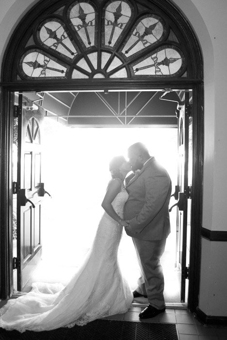 Черно-белая фотография молодоженов, целующихся под арочным проемом - советы по освещению свадебной фотографии