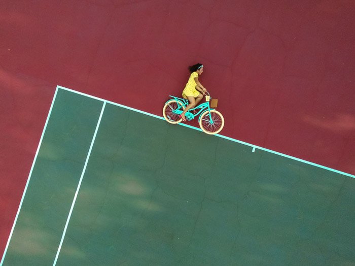 Оптическая иллюзия фото девушки на велосипеде, которая выглядит так, будто едет по абстрактным линиям