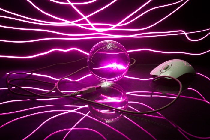 Атмосферная фотография стеклянного шара, компьютерной мыши и кабеля в окружении потрясающей пурпурной светописи