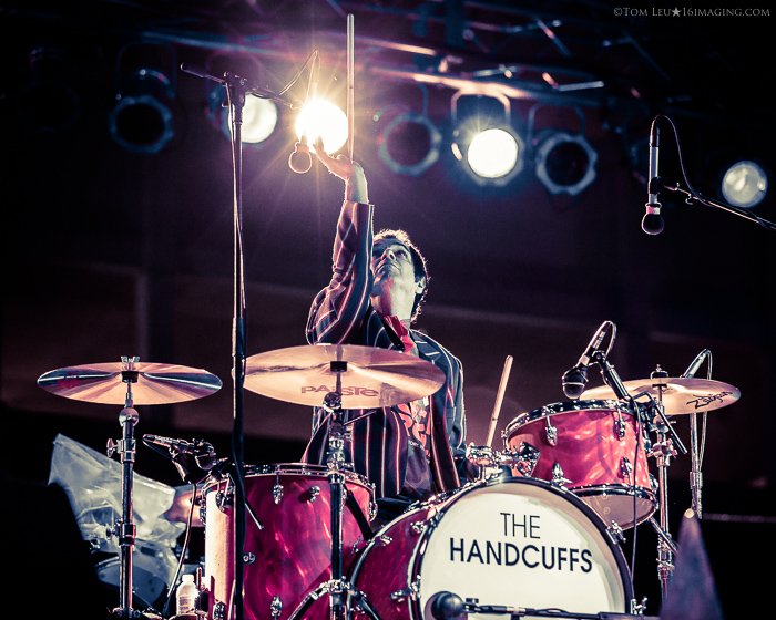 A music photography live shot of the drummer playing onstage