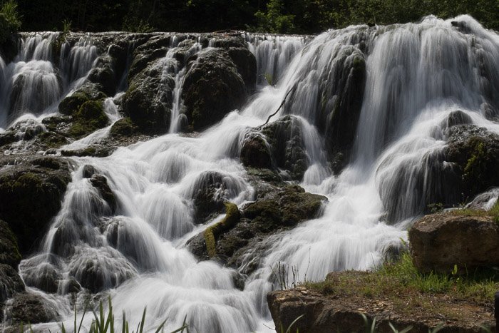Красивый струящийся водопад снят с длинной выдержкой, чтобы создать размытость движения воды и создать впечатление текучести. 