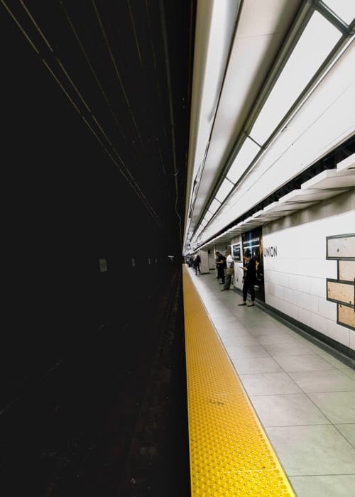 Темный тоннель метро на одной половине, и люди, ожидающие на светлой платформе