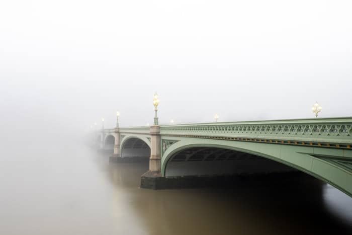 Атмосферный снимок зеленого моста, исчезающего в тумане
