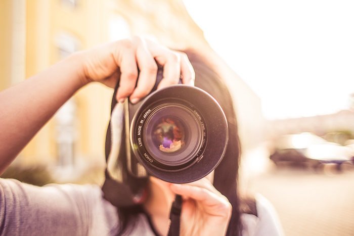 Девушка направляет камеру на фотографа на мягком размытом фоне - советы по страхованию фотографии и камеры