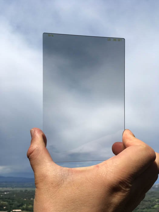 Человек держит фильтр объектива на фоне неба