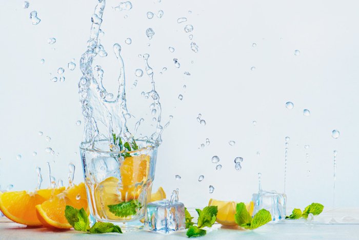 креативная фуд-фотосессия с апельсинами и брызгами воды на белом фоне
