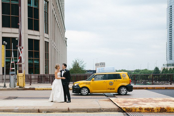 недавно поженившаяся пара позирует на улице перед желтым такси