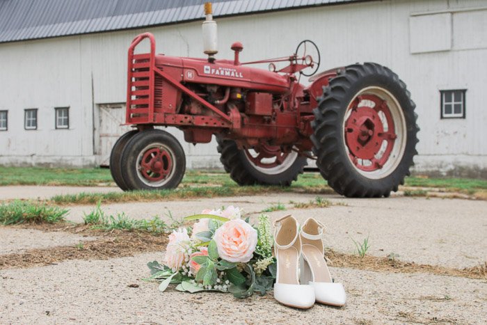 Юмористическая свадебная фотография натюрморт свадебных аксессуаров на земле перед красным трактором