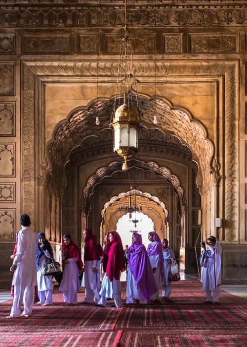 Человеческий фактор в архитектурной фотографии: Группа людей идет через мечеть Бадшахи в Лахоре, Пакистан