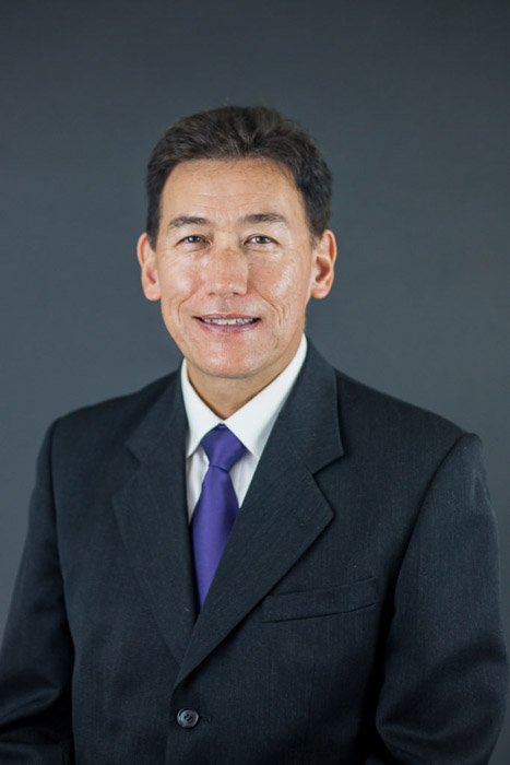 Корпоративный снимок мужчины в деловом костюме на простом сером фоне