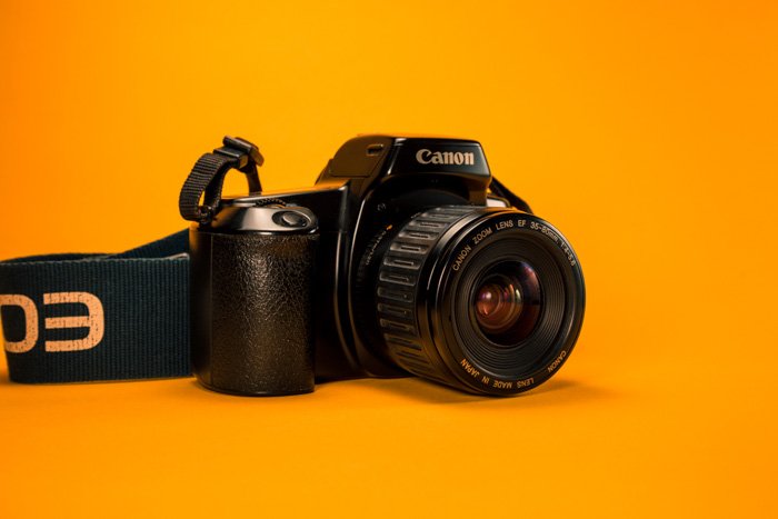 камера canon DSLR на ярко-оранжевой поверхности