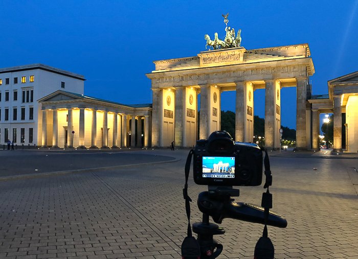 DSLR камера на штативе фотографирует Бранденбургские ворота в Берлине ночью