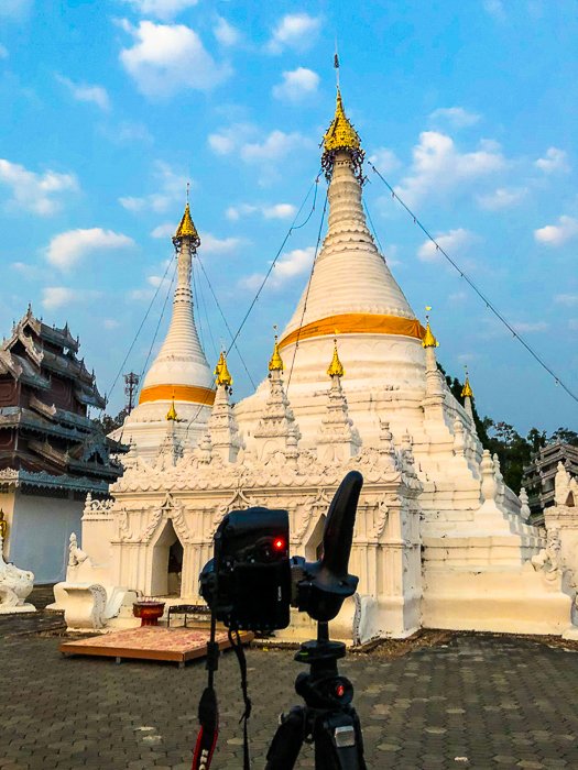 Камера на штативе готова к съемке Бхуддистской ступы на фоне ярко-синего неба ранним утром