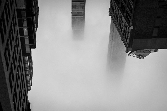 Архитектурная фотография, сделанная абстрактно: Атмосферный снимок трех зданий, выходящих из Манхэттена в тумане. New York, NY, USA