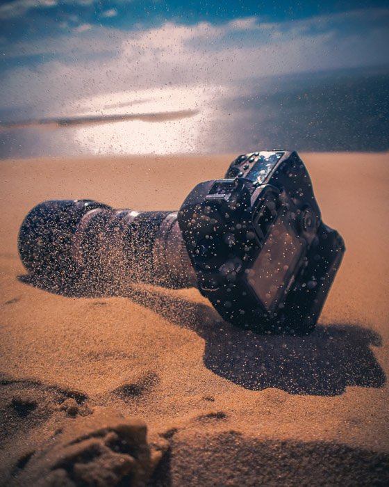 DSLR камера лежит в песке на пляже