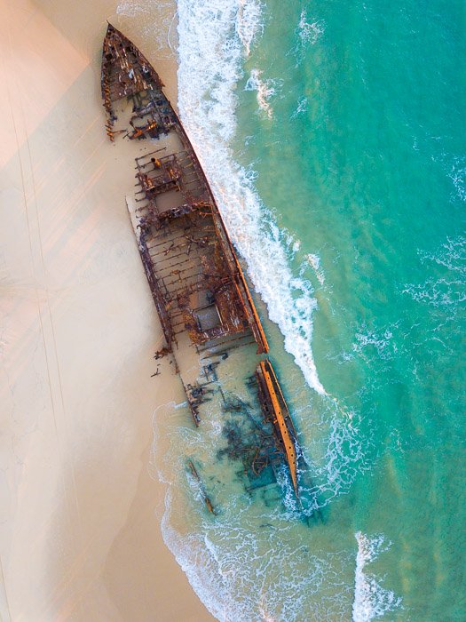 вид с воздуха на затонувший корабль на тропическом берегу