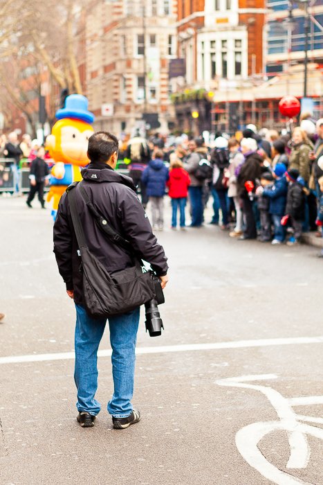 Мужчина с зеркальным фотоаппаратом наблюдает за толпой на карнавале
