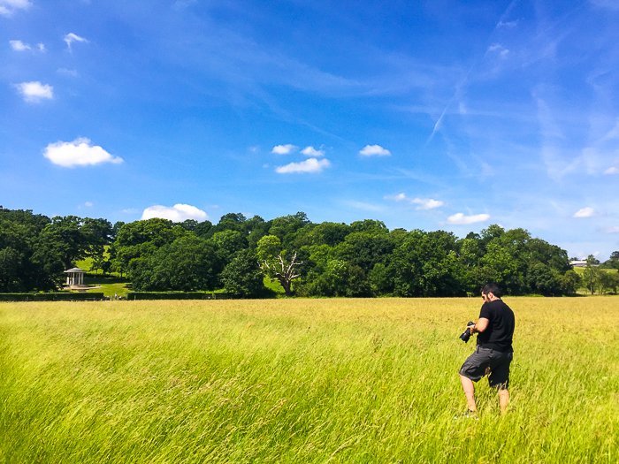 Фотограф проверяет настройки своей камеры в красивом сельском пейзаже ясного дня
