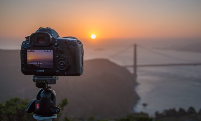 DSLR камера установлена на штатив Manfrotto для съемки красивого заката