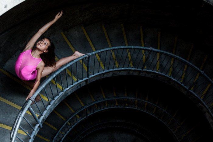 Молодая девушка в розовом балетном платье танцует на темной лестнице - лучшие настройки для портретов