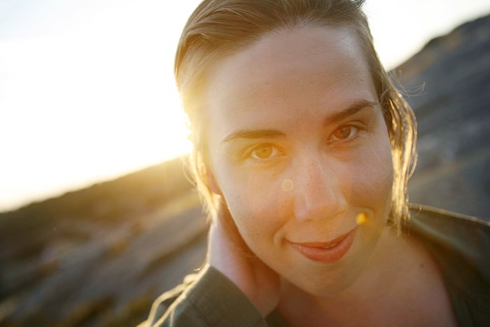 Портрет улыбающейся женщины на закате крупным планом.
