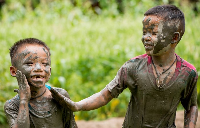 Два смеющихся тайских мальчика, покрытых грязью - фигурная фотография