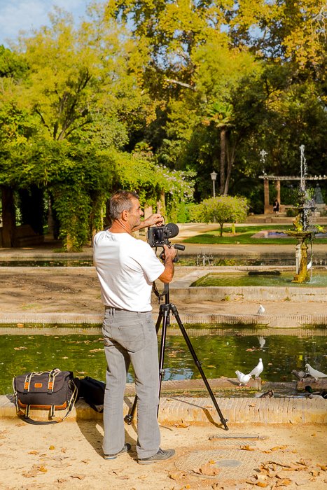 фотография мужчины на берегу озера, устанавливающего камеру на штатив