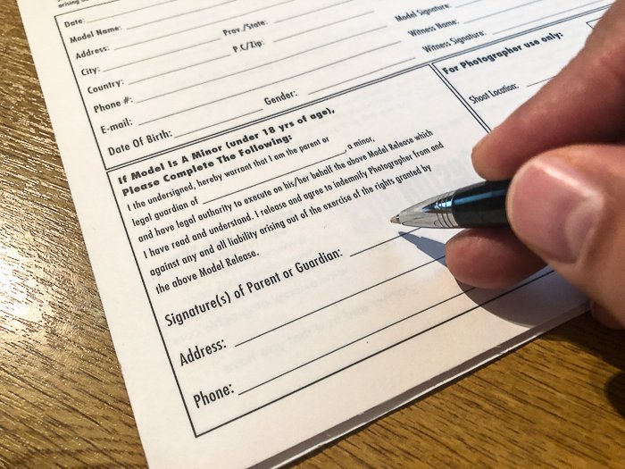 close up photo of the hand holding a pen near a form to sign - How to Take Stock Photos That Sell