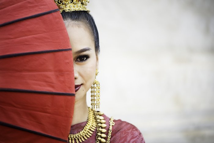 Интересная идея композиции фотографии красивой тайской девушки, половина лица которой закрыта зонтом