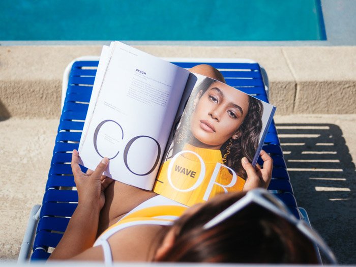Девушка читает модный журнал, загорая на шезлонге - советы фотографа