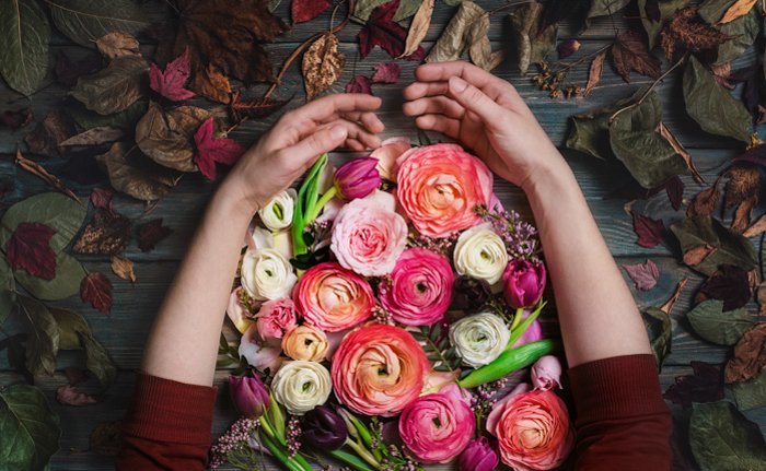 руки, ласкающие букет ярких цветов на деревянном столе как альтернатива креативному фону для фото