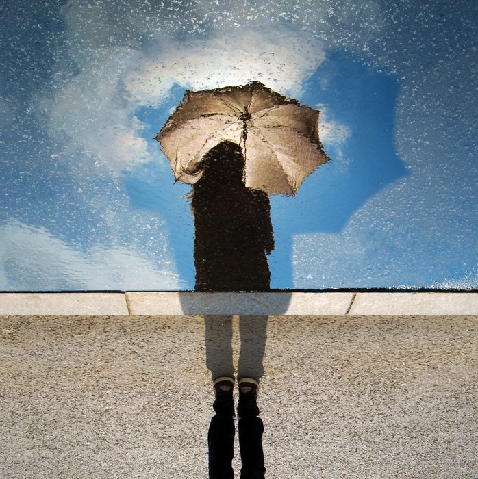 Креативное фото дождя человека, держащего зонт, отражающегося в забрызганном дождем окне