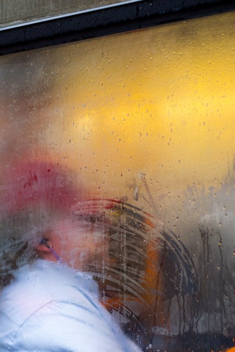 Портрет человека, снятый через забрызганное дождем окно