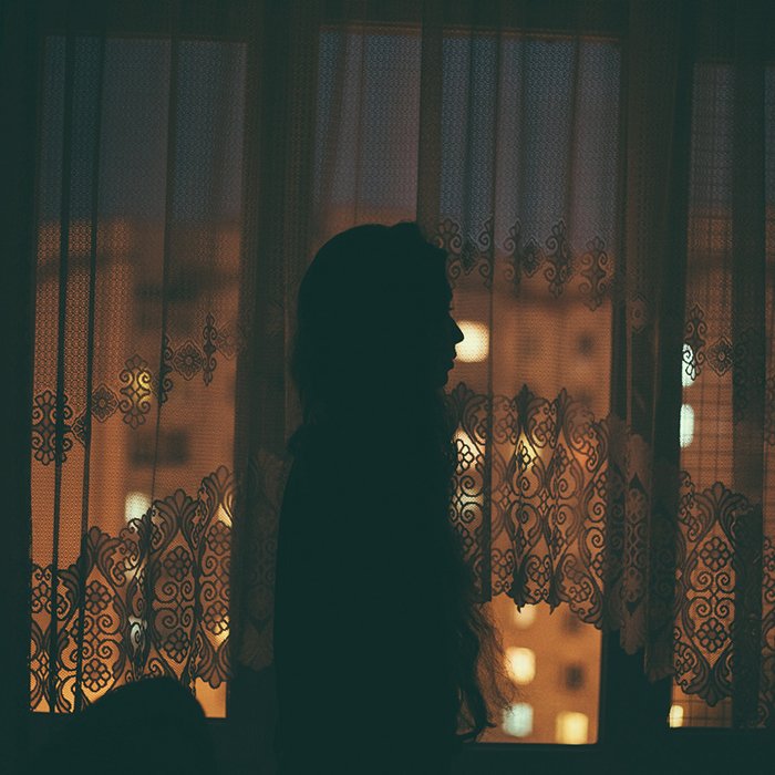 Атмосферный портрет женщины-модели, позирующей на фоне окна ночью - креативные позы для селфи и идеи