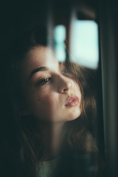 Атмосферный портрет женщины-модели, смотрящей в окно - отличное позирование для селфи