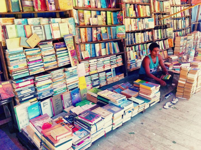 Уличная фотография продавца, присматривающего за своим книжным киоском