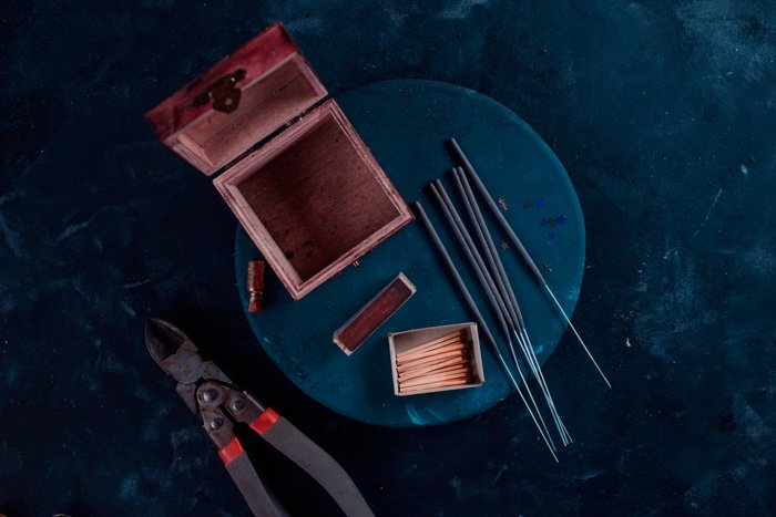 Фотография с искрами: Пустой открытый деревянный ящик, искры, спички и кусачки на столе
