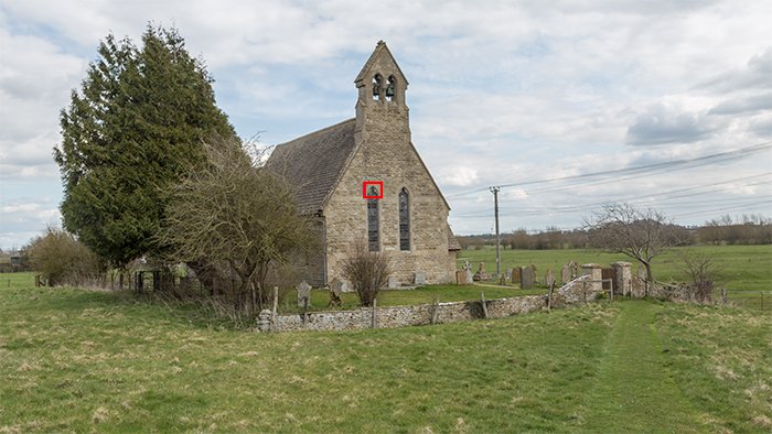 Небольшая каменная церковь в сельском пейзаже с выбранным и выделенным красным цветом визуальным якорем